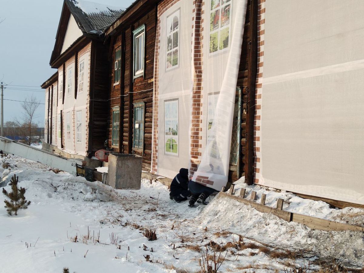 В Кемеровской области жилой деревянный барак завесили баннером с фотографией нового дома перед приездом губернатора.